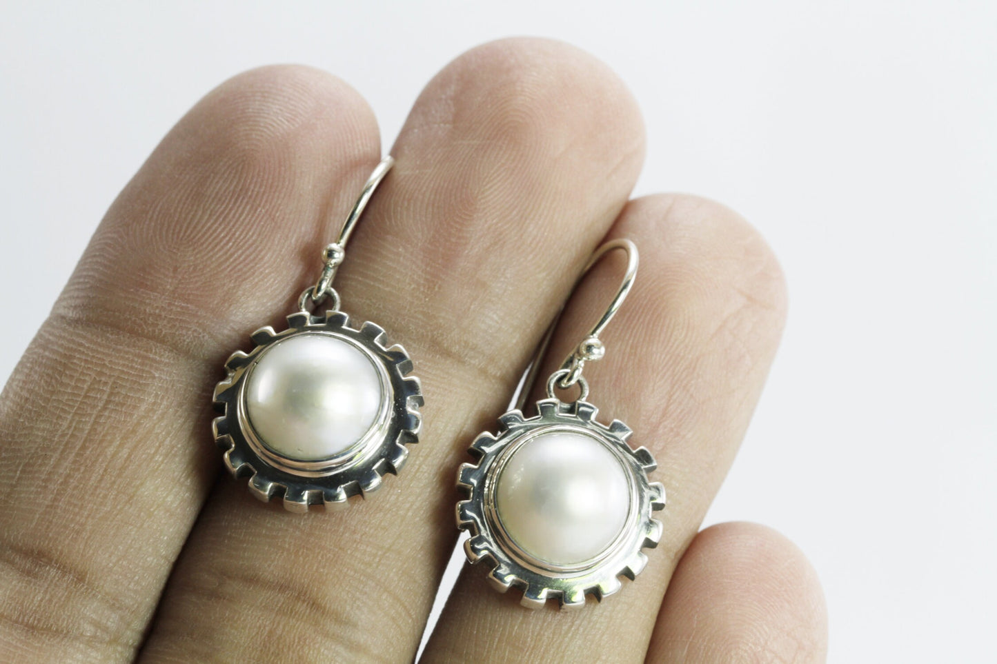 white mabe pearl earrings set in 925 sterling silver decorated with gear style ornament