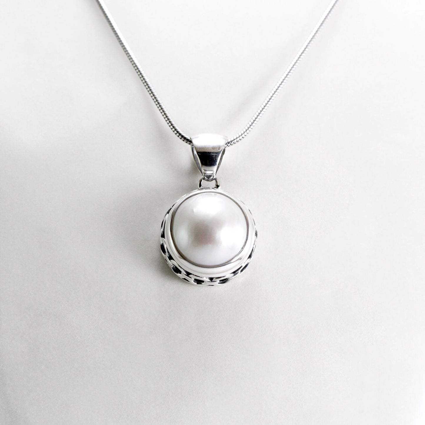 White mabe pearl pendant 13 mm round set in 925 sterling silver decorated with chain carving edge